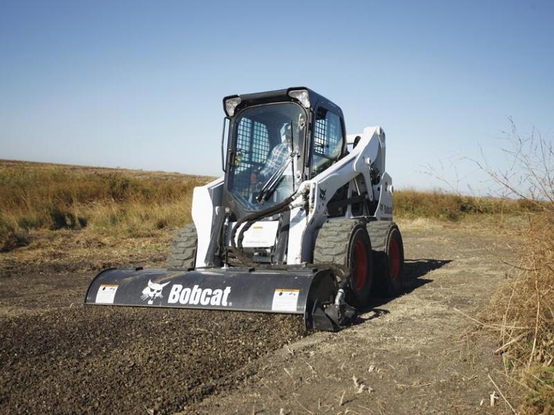 Bobcat skid steer with rotary tiller attachment preparing soil